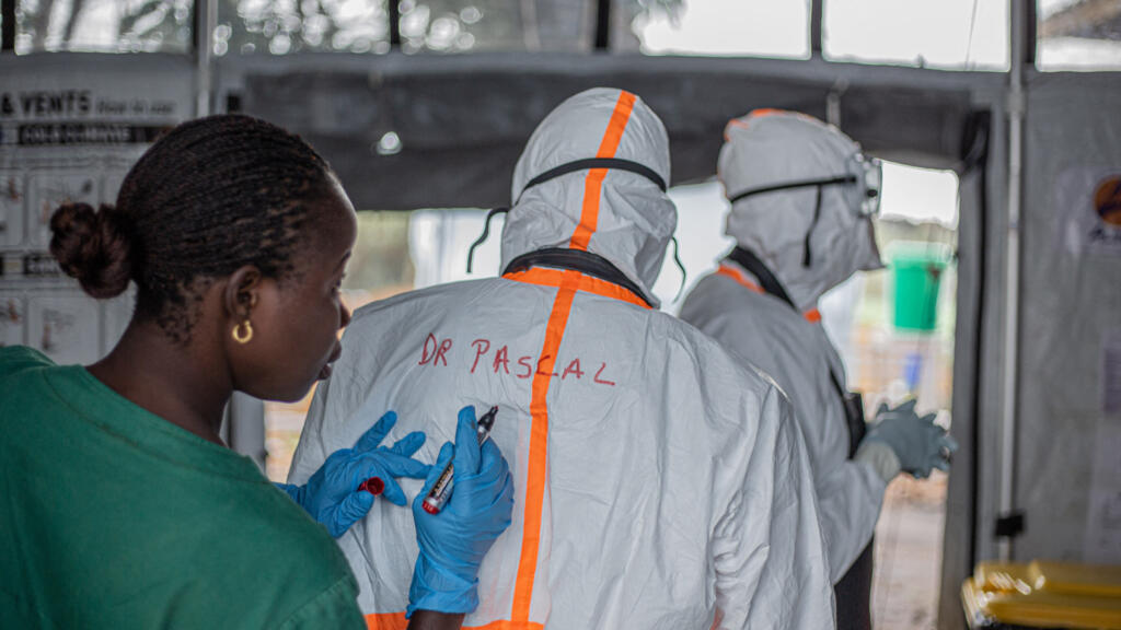 A health worker writes a doctor's name on the back of their personal protective equipment (PPE) before entering the Ebola treatment center (ETC) in Rwampara to treat patients infected with the Ebola virus disease, in Bunia (Ituri), eastern Democratic Republic of Congo, July 13, 2026.