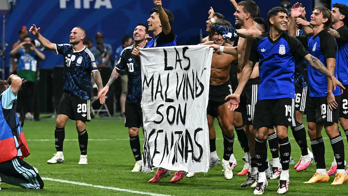 Argentine soccer players holding a banner that reads 'Las Malvinas son argentinas'