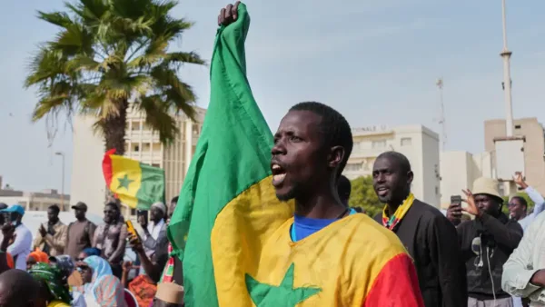 A protester in Dakar, Senegal, holds anti-government signs during a demonstration on March 6, 2026.
